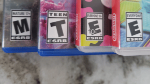 The ESRB logo on four different video game covers lined up on a kitchen counter.