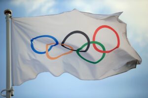The Olympic flag blowing in the wind on a sunny day.